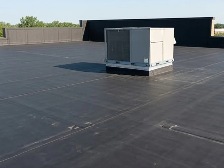Flat black EPDM rubber roof with a rooftop HVAC unit, dry day