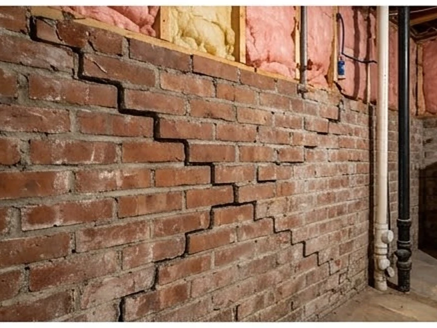 Step crack in a brick foundation, unfinished basement: foundation inspection in Minneapolis, MN