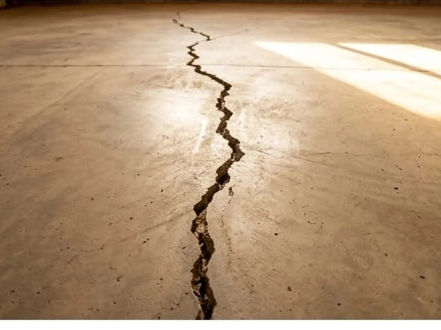 Slab-on-grade garage floor crack, summer light: foundation inspection in Minnesota and Iowa