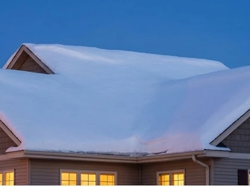 Heavy snow load on a roof, dusk: roof inspection in Shoreview, MN